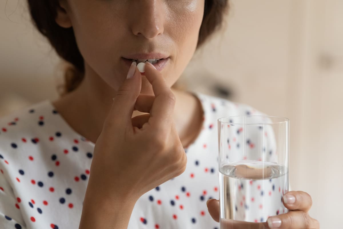 Frau nimmt Tablette mit Wasser ein
