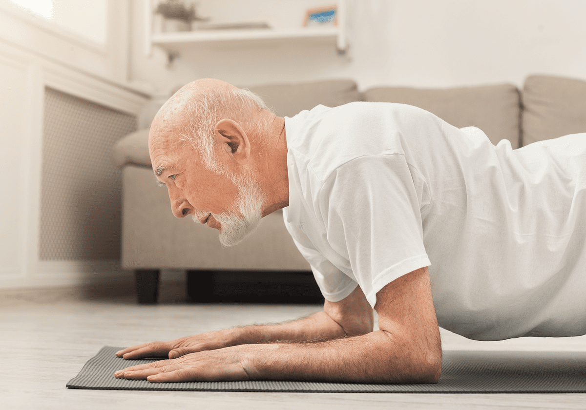 Älterer Mann macht Fitnessübungen im Wohnzimmer